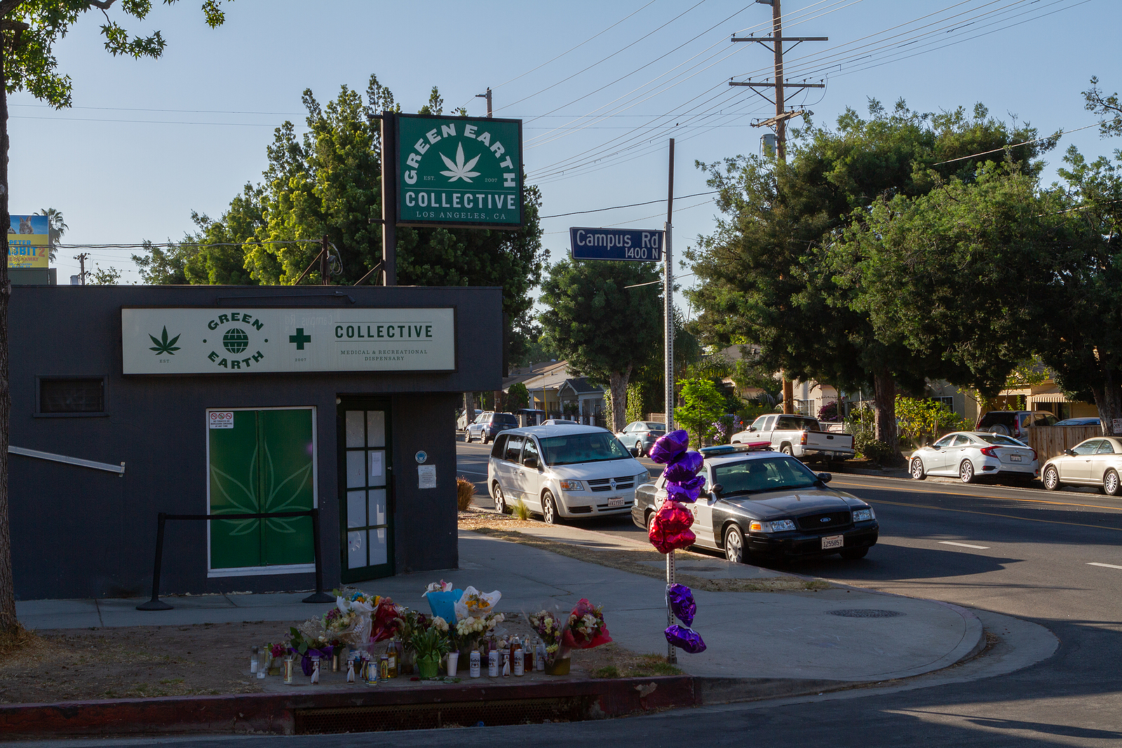 photo of low income neighborhood with memorial balloons and flowers by the street