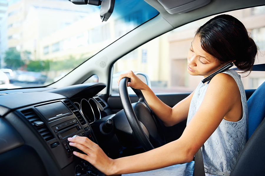 Woman talking on the phone and adjusting the radio while driving